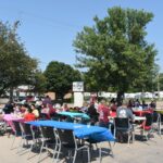 Grand Prairie Foods employees eating outside at tables during their summer party